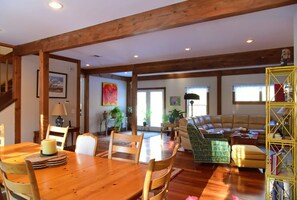 A spacious living room with a wooden dining table, a sofa, and a bookshelf. - Peaceful, Post and Beam Loft, Sleeps 9 (New Marlborough)