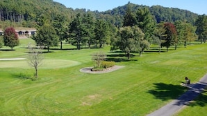 Un campo de golf con club house, árboles y cielo despejado.