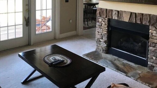 Una sala de estar con chimenea, un televisor montado encima y un ventilador de techo.