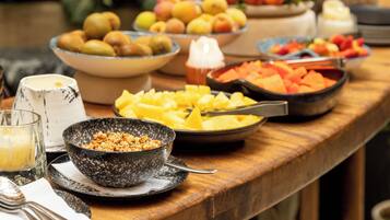 A buffet table with various fruits and dishes, a rustic wooden table, and a hanging rope decoration.