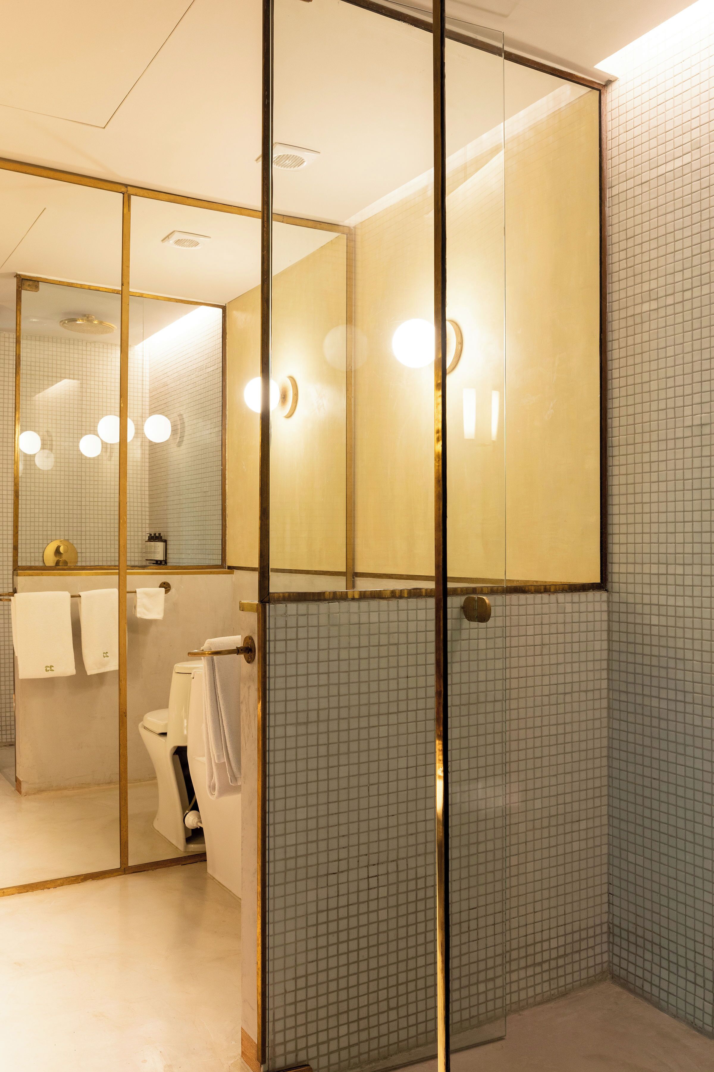 A modern bathroom with a glass partition, a toilet, a sink, and a mirror.