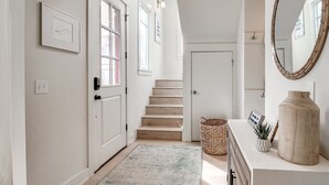 Ein Flur mit Treppe, einer Tür, einem Wandspiegel und einem kleinen Korb.