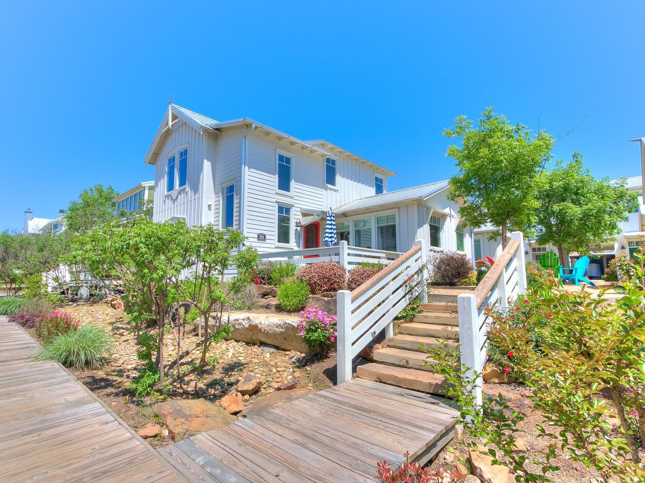 A white two-story house with a wooden deck and a white fence.