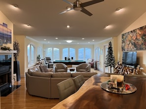Relax in this spacious living area with a high ceiling, featuring a large sectional sofa, coffee table, and mounted TV.