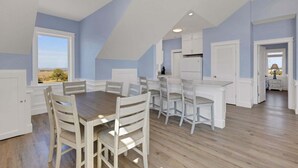 A spacious dining area with a high ceiling and natural light from windows.