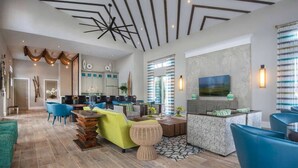 Un salón amplio con un diseño moderno en el techo, una zona de cocina con una isla grande y un comedor con sillas azules.