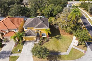 A two-story house with a red-tiled roof, a garage, and a well-maintained lawn.