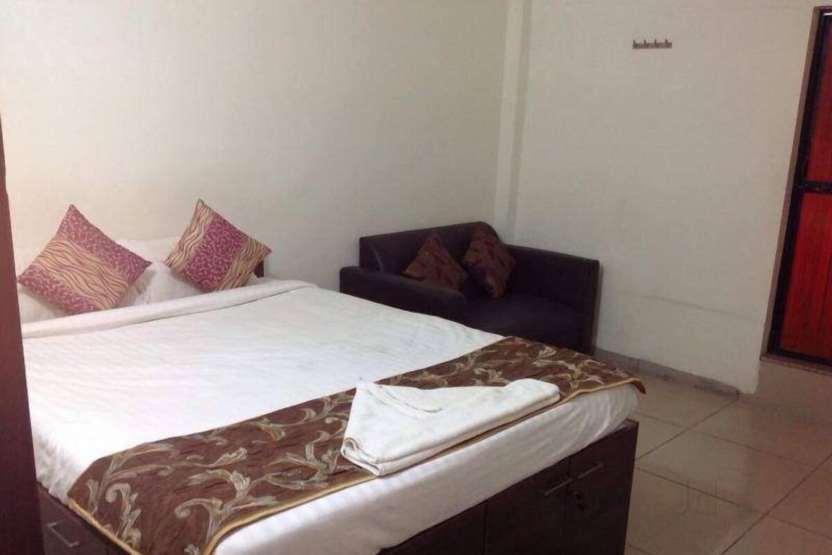 A bedroom with a bed, a sofa, and a wardrobe.