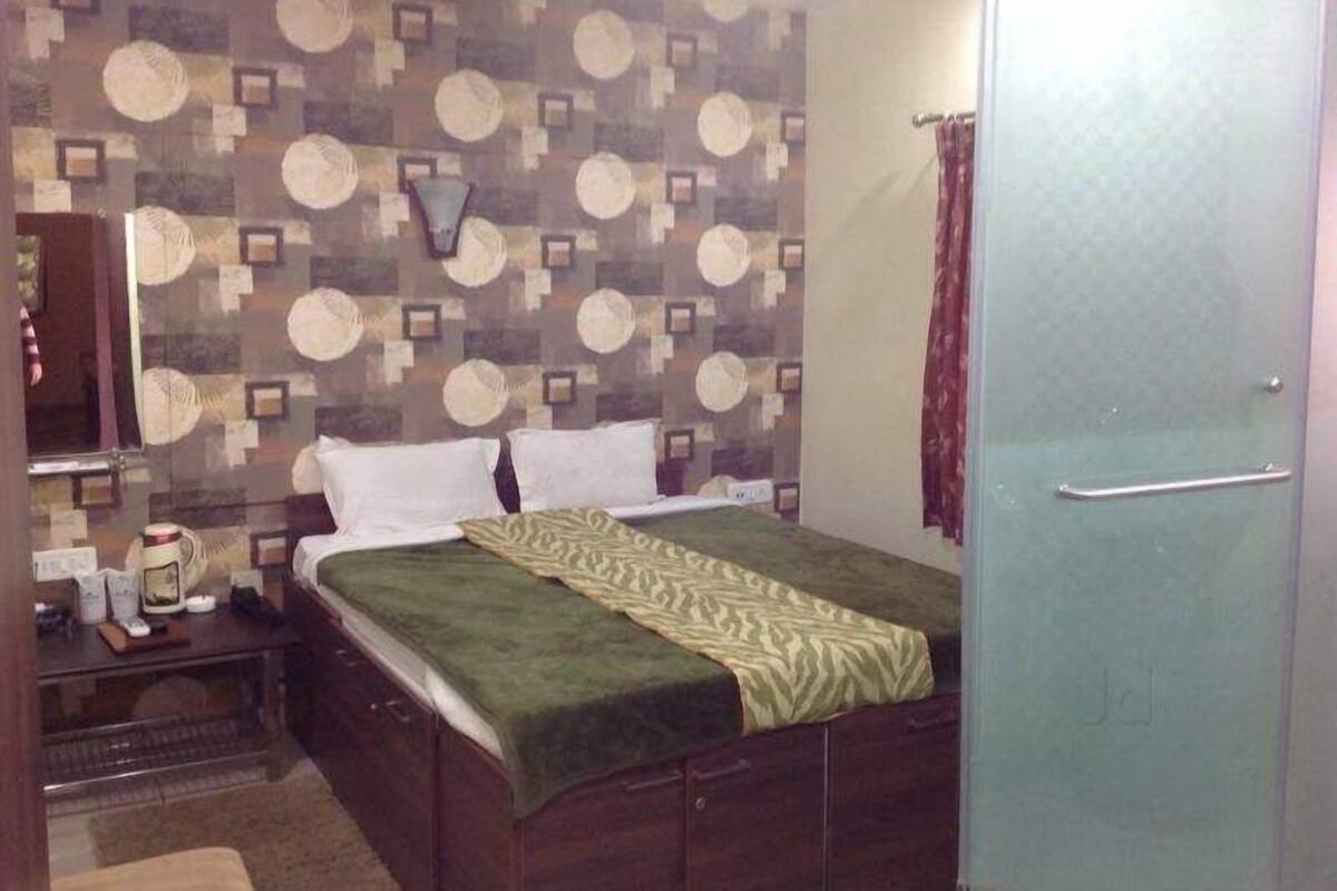 A bedroom with a bed, a nightstand, a dresser, and a mirror.