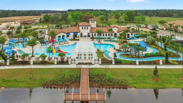 Un parque acuático con varias piscinas, toboganes y una terraza de madera sobre el agua.