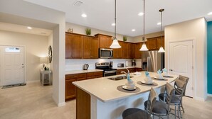 Una cocina moderna con armarios de madera, electrodomésticos de acero inoxidable y una isla central con taburetes de bar.