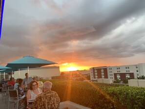 A rooftop dining area with outdoor seating and a view of the sunset. - Condo at golf & country club overlooking preserve and course.  Pet friendly! (Punta Gorda)