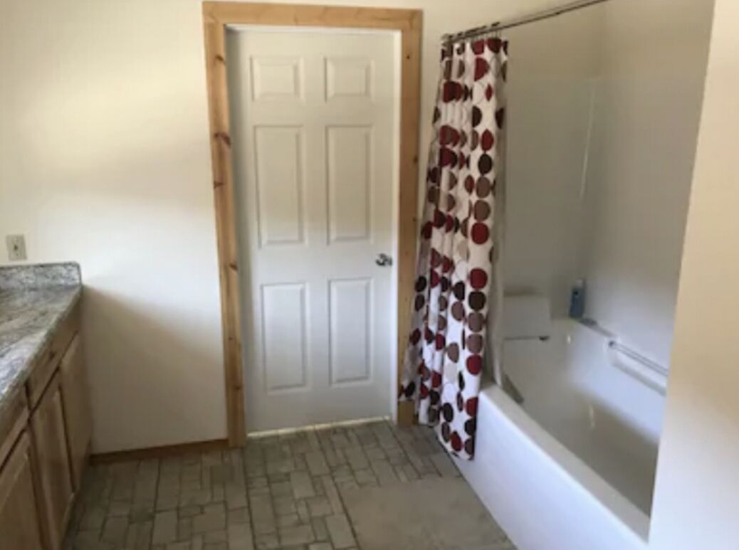 A bathroom with a shower, a bathtub, and a door.