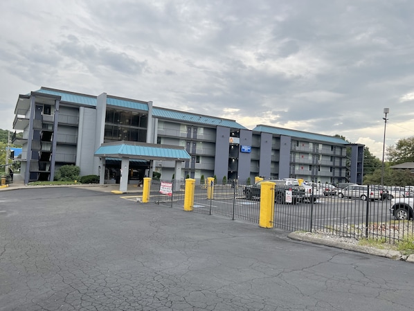 A multi-story hotel with a blue roof and a parking lot.
