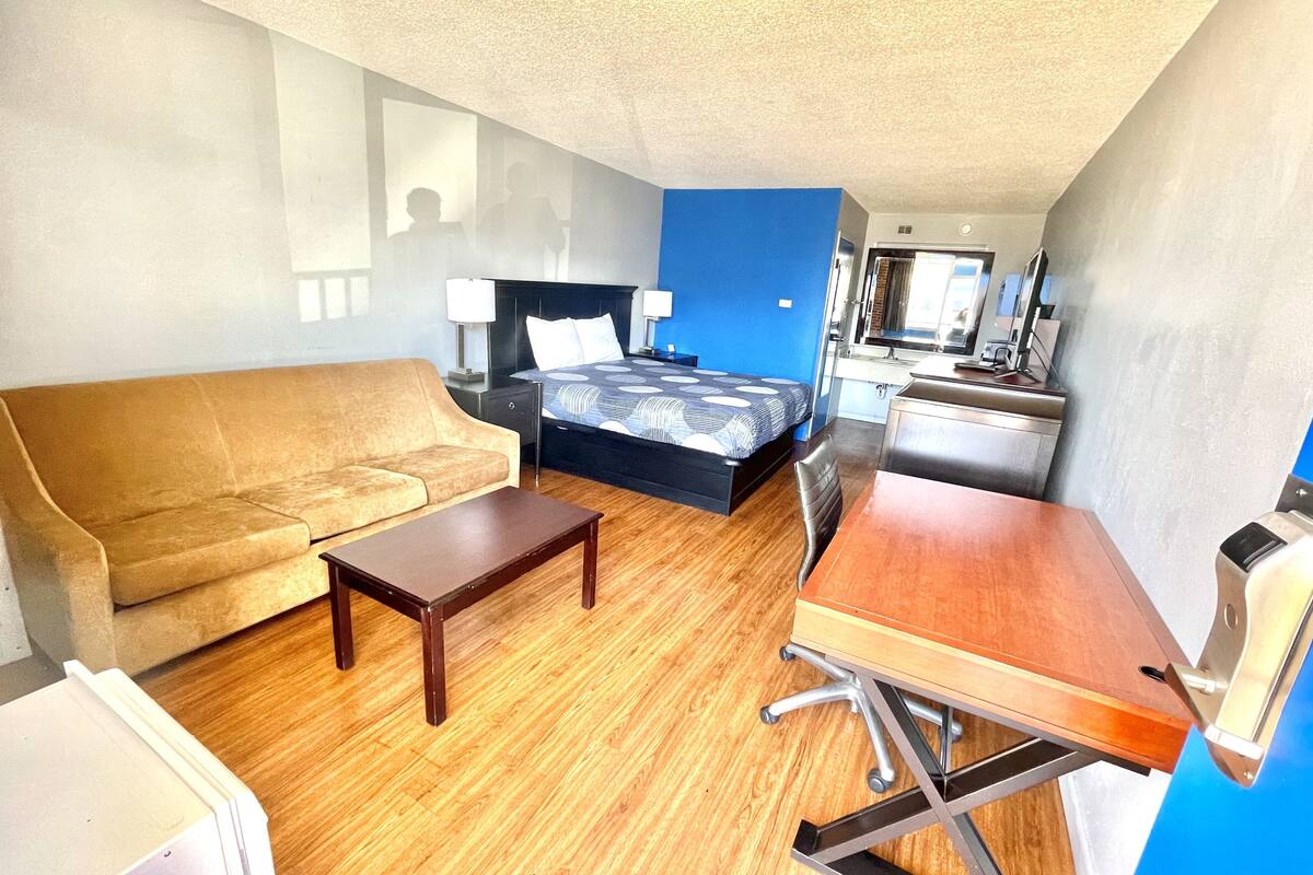 Une chambre d’hôtel équipée d’un canapé, d’un lit, d’un bureau et d’une kitchenette.
