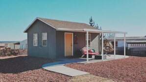 A small, single-story house with a porch, a red chair, and a covered outdoor seating area. - The Bird House near Zion & Bryce  (Kanab)