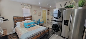 Un dormitorio pequeño con cama, lavadora y refrigerador.