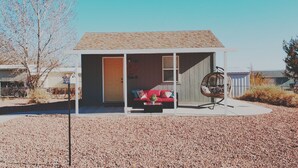 A small, single-story house with a red couch and a swing chair outside. - The Bird House near Zion & Bryce  (Kanab)