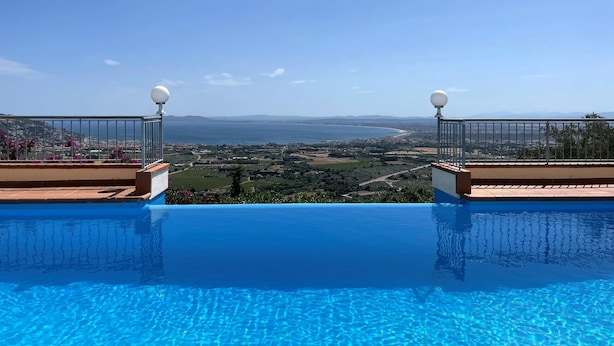 Piscina azul cristalina con vistas a un paisaje costero y montañas a lo lejos.
