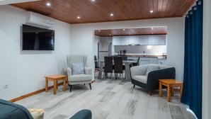 A modern living room with a dining area, kitchen, and a TV mounted on the wall. - Beautiful country Villa with a small house onsite which together sleeps 6 people (Estreito da Calheta Madeira)