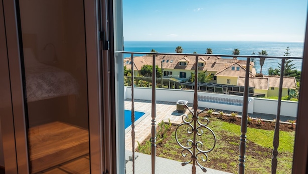 A balcony with a view of a swimming pool and a residential area. - Beautiful country Villa with a small house onsite which together sleeps 6 people (Estreito da Calheta Madeira)