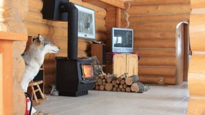 En stuga byggd av timmer med en vedeldad kamin, en tv och en öppen spis.