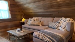 Una habitación acogedora con sofá, una mesita y una lámpara colgante.