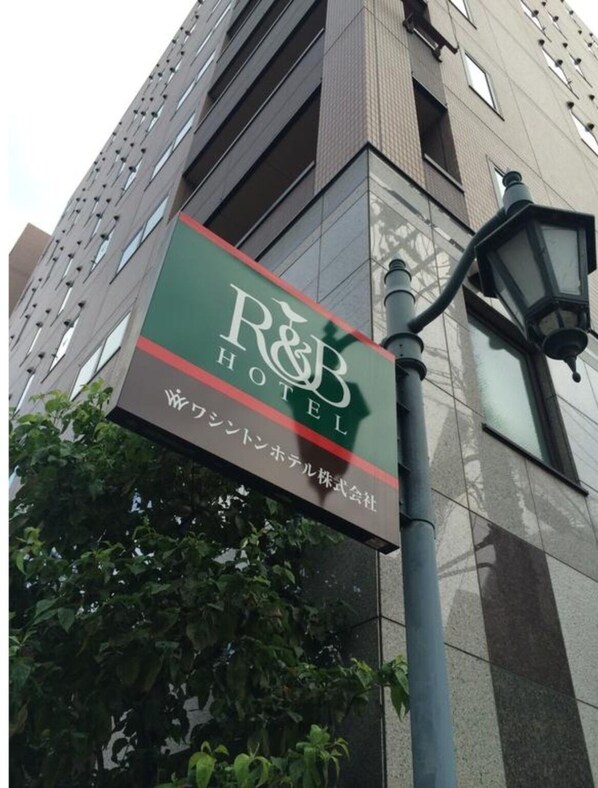 Une enseigne d’hôtel avec l’inscription « R&B Hotel » et du texte en japonais.