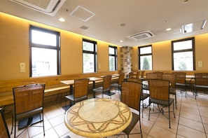 Un espace repas avec des tables et des chaises hautes, de grandes fenêtres et un pilier central.