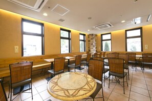 Un comedor con mesas y sillas altas, ventanas amplias y un pilar central.