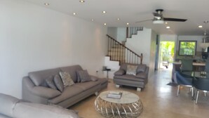 Ein modernes Wohnzimmer mit einer Couch, einem runden Couchtisch und einer Treppe, die in eine weitere Ebene führt.