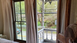 Un dormitorio con un ventanal grande, un abanico de madera y vistas a la calle y al jardín.