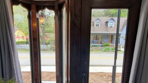 Vista desde una habitación con un ventanal, una puerta y una pequeña mesa con una planta.