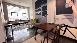 A dining area with a wooden table and chairs, a patterned rug, and a large window with a view. - Stay Roanoke | Luxe Loft | Arts & Ale (Roanoke)