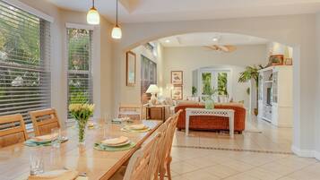 A spacious dining area with a long table, chairs, and hanging pendant lights.