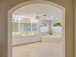 Une salle de bain moderne avec un grand meuble-lavabo, une baignoire et un ventilateur de plafond.