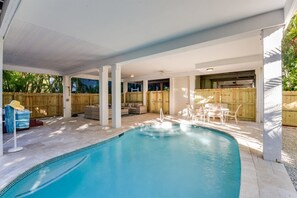 Un espace piscine couvert, doté d’un coin salon aménagé et d’une clôture en bois.