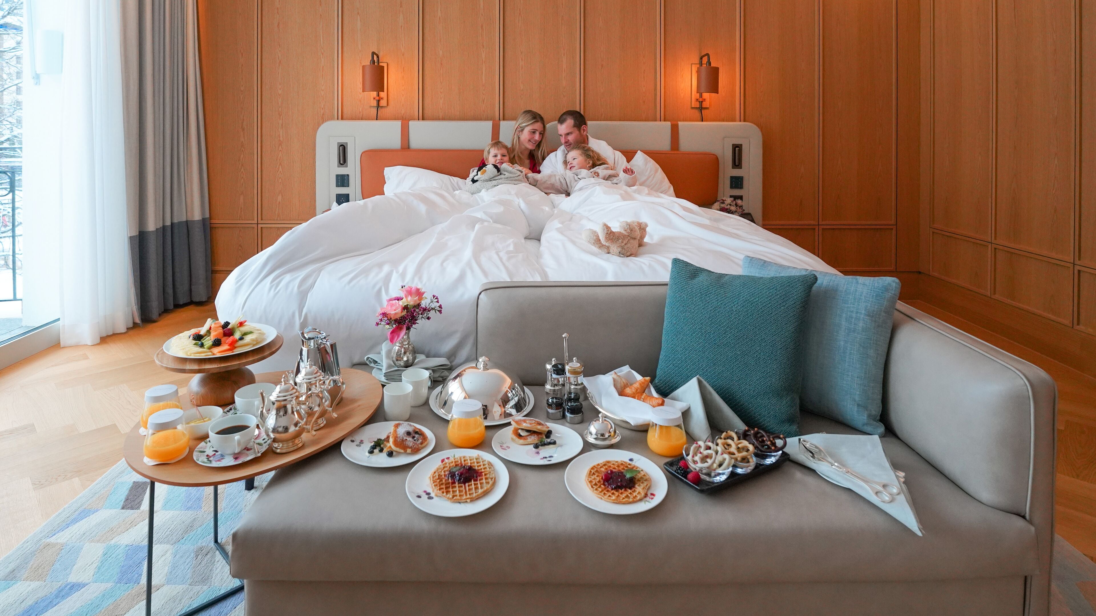 A hotel room with a bed, bedside tables, a breakfast tray, and a view of the outdoors.