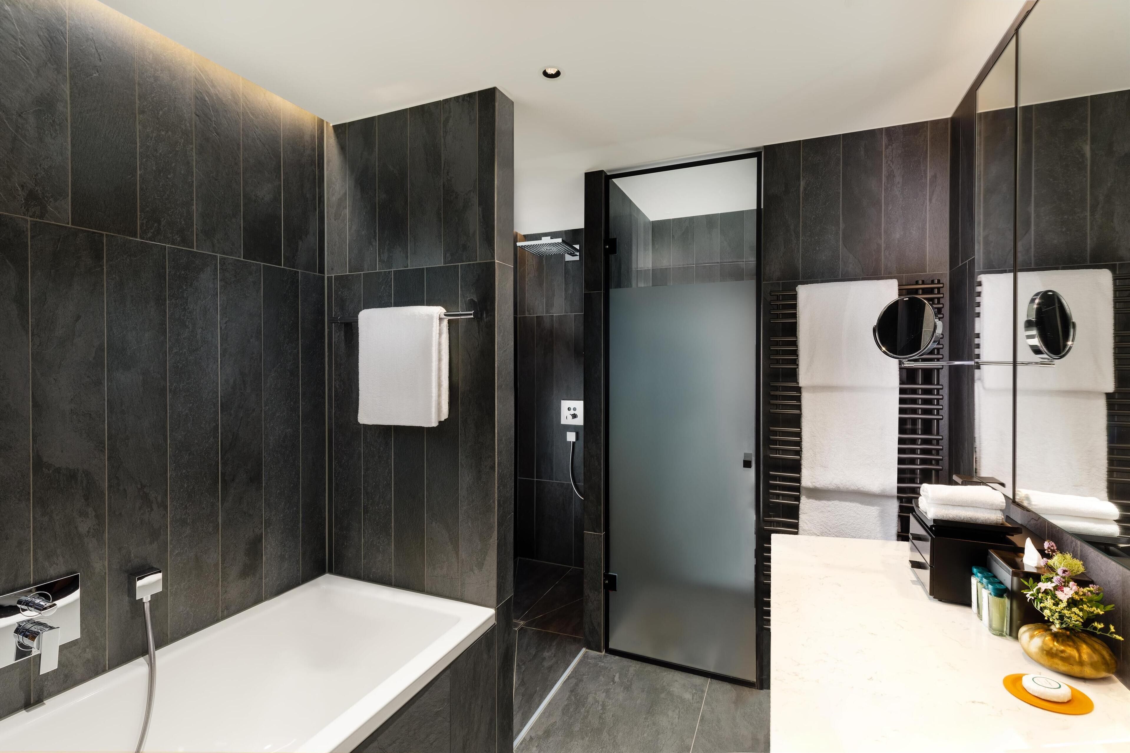 Ein modernes Badezimmer mit Badewanne, Duschkabine und Waschtisch mit Spiegel.