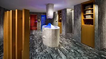 A modern hotel lobby with a marble floor, a central ice sculpture, wooden partitions, and a blue door in the background.