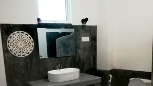 Un baño con lavamanos blanco, espejo, inodoro y ducha.