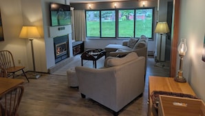 Una sala de estar con chimenea, sofá y televisor montado en la pared.