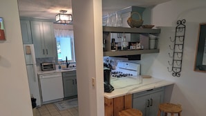 Una cocina con armarios azul claro, encimera blanca y un taburete de madera.