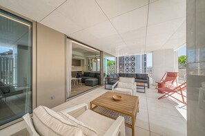 A modern living area with a sofa, chairs, a table, and a glass partition.