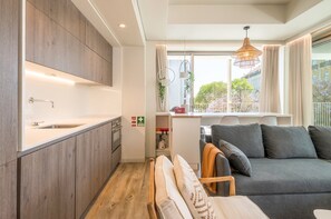 Une cuisine moderne avec des meubles en bois, un four encastré et une fenêtre donnant sur les arbres.