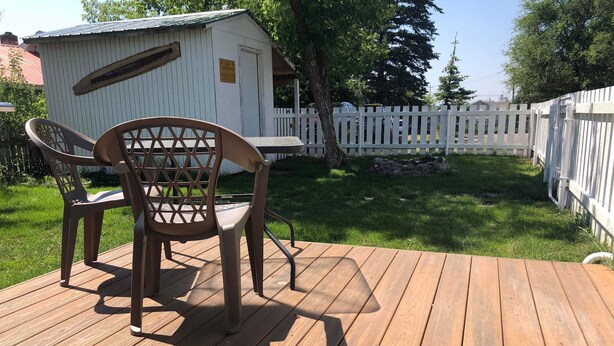 A wooden deck with two chairs and a small shed in the background. - Teakettle Kottage (Columbia Falls)