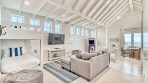 A spacious living area with a high ceiling, a sofa, a television, and a gaming console. - h2o365-The Heart of Seagrove (Santa Rosa Beach)