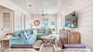 A spacious living room with a large L-shaped sectional sofa, a wooden coffee table, and wicker chairs. - h2o365-The Heart of Seagrove (Santa Rosa Beach)