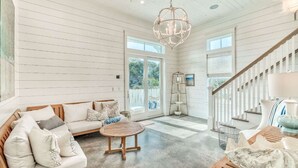 A spacious living room with a wooden sofa, a round coffee table, and a chandelier. - h2o365-The Heart of Seagrove (Santa Rosa Beach)