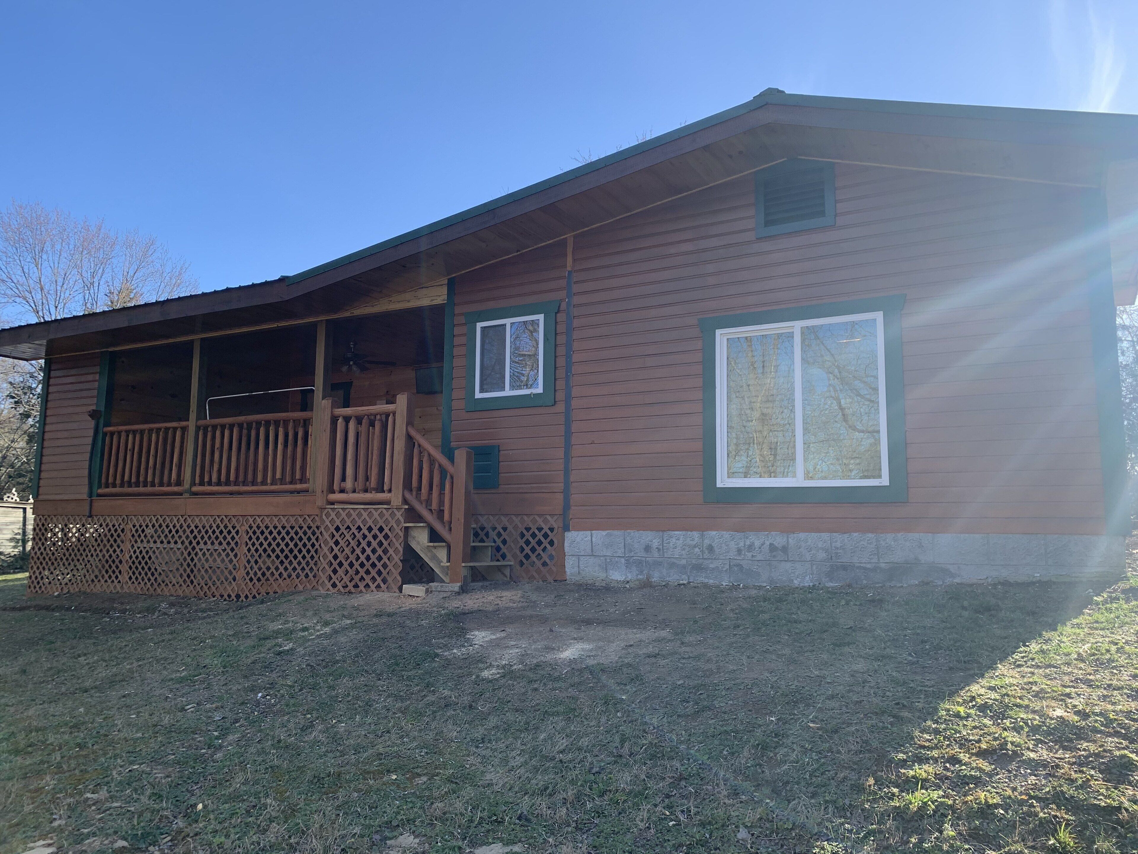 A single-story cabin with a wooden deck and a covered porch.